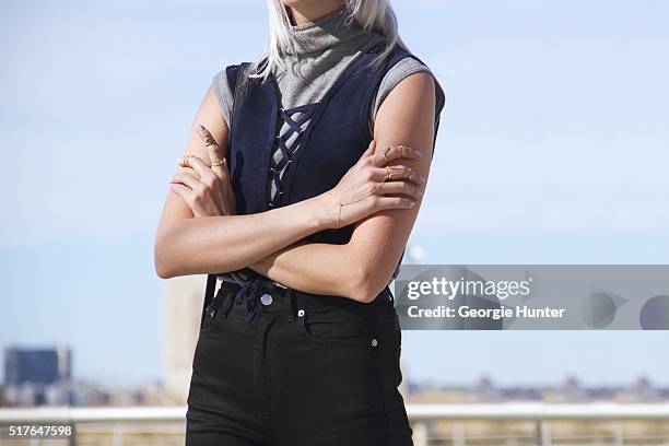 Emily Mercer wearing vintage grey turtleneck sleeveless sweater, blue Urban Outfitters navy top with tie, black high waisted BLK DNM pants, left hand...