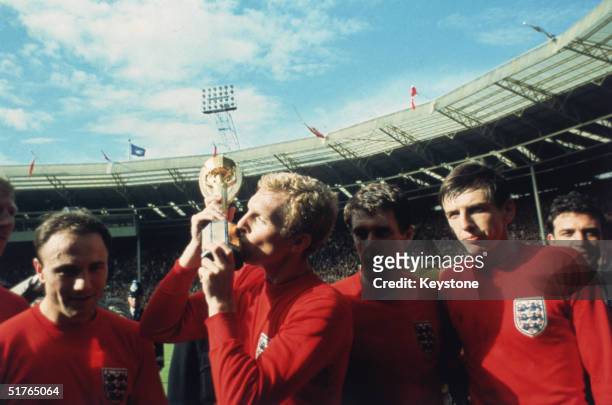 England captain Bobby Moore kissing the Jules Rimet trophy as the team celebrate winning the 1966 World Cup final against Germany at Wembley Stadium....