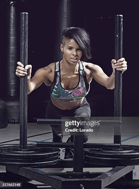 beautiful brunette athletic woman posing with equipment in a gym - sled push stock pictures, royalty-free photos & images