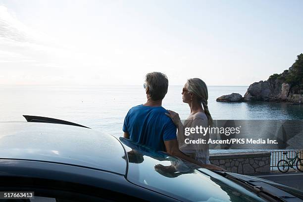 couple stand beside car above road,look out to sea - look back 個照片及圖片檔