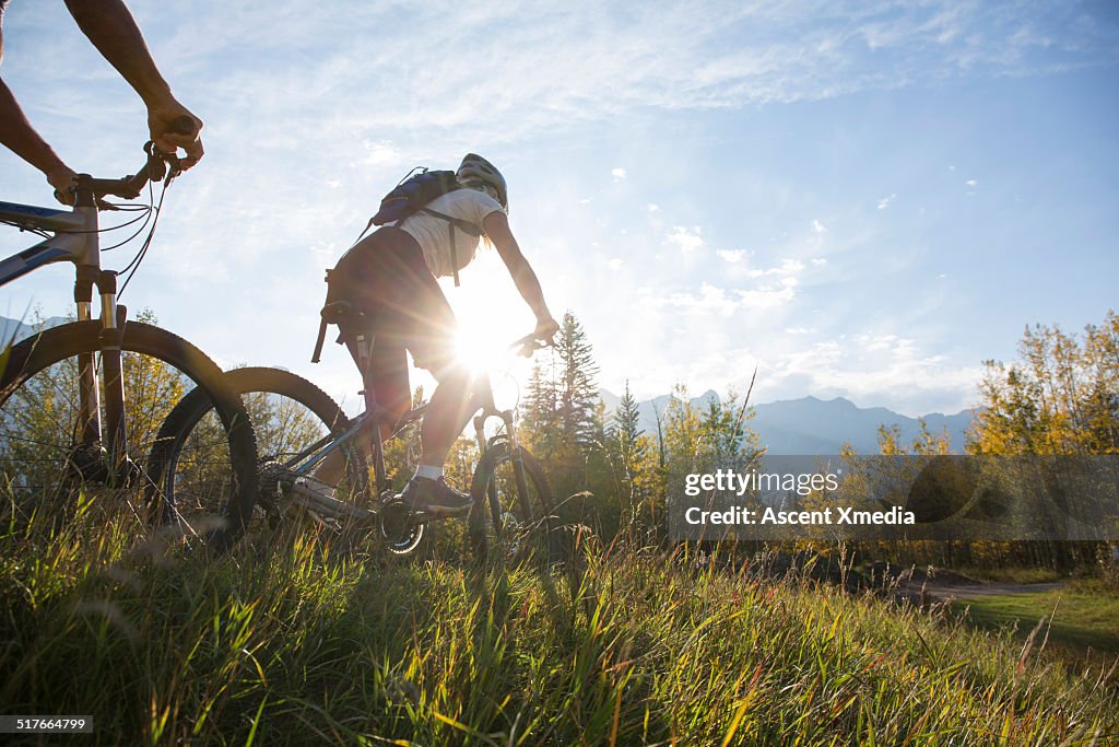 Mountain bikers descend mtn ridge crest, autumn