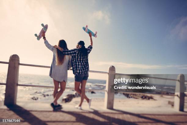 hipster girls with skateboards on summer day at the beach - girl roller skates stock pictures, royalty-free photos & images