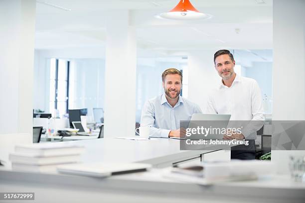businessmen with laptop at desk in office - standing together stock pictures, royalty-free photos & images