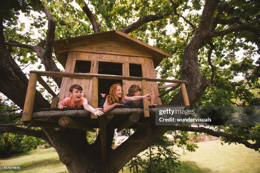 Childhood friends in a treehouse laughing and pointing