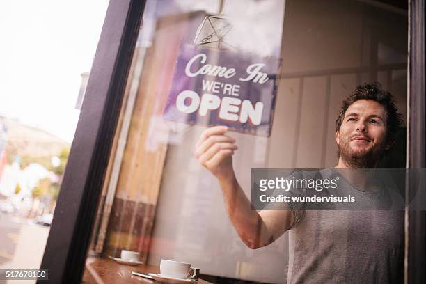 hipster uomo girando porta apertura di caffè negozio - inaugurazione foto e immagini stock