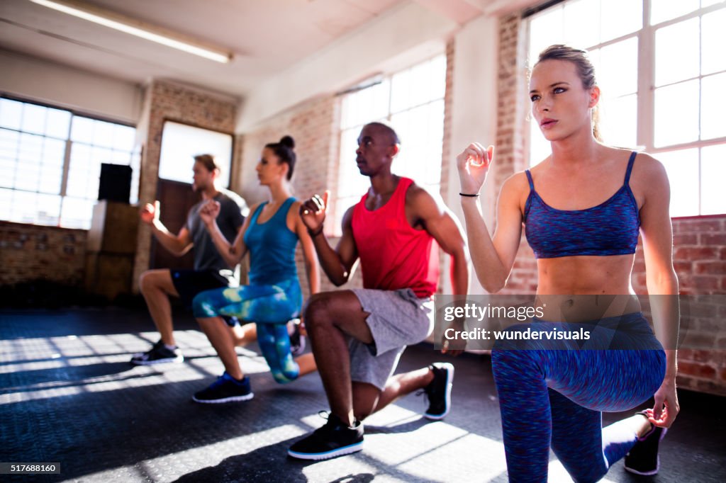 Friends doing lunges during a workout in the gym