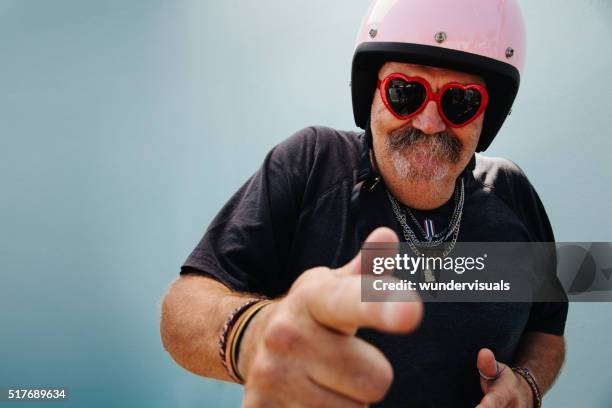 funny grandpa with pink helmet and heart sunglasses - one finger stockfoto's en -beelden