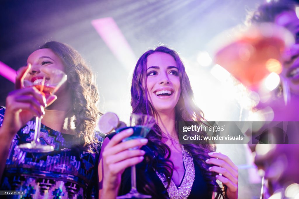Young friends enjoying party with colorful drinks at the club