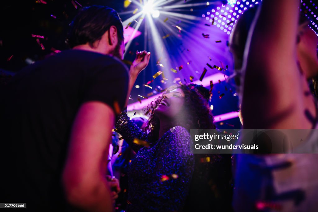 Young friends having fun with confetti on night club party