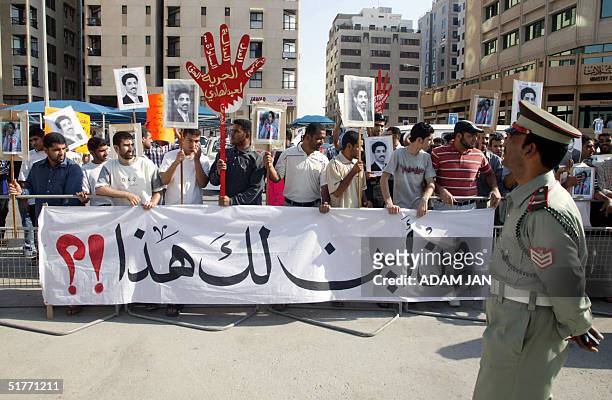 Bahrainis holding pictures of human rights activist Abdul Hadi al-Khawaja and a banner against corruption take part 21 November 2004 in a protest in...