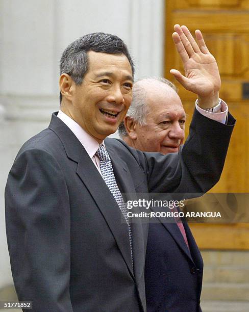 Singapore's Prime Minister Lee Hsien Loong waves next to Chilean President Ricardo Lagos as he enters at La Moneda Presidential Palace to attend the...