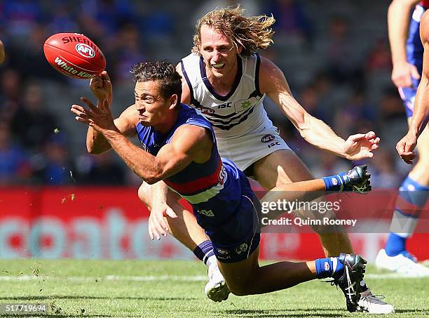 Luke Dahlhaus of the Bulldogs handballs whilst being tackled by David Mundy of the Dockers during the round one AFL match between the Western...