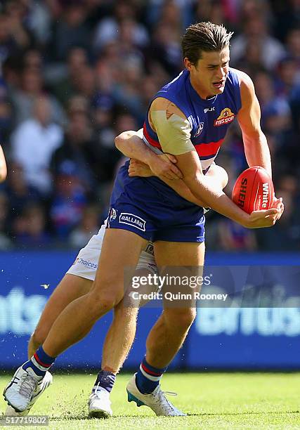 Tom Boyd of the Bulldogs handballs whilst being tackled by Lachie Neale of the Dockers during the round one AFL match between the Western Bulldogs...