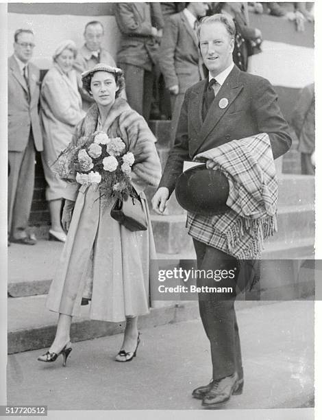 Carrying a bouquet of carnations, Britain's Princess Margaret arrives at the Edinburgh Horse Show to present the prizes. With her is the Earl of...
