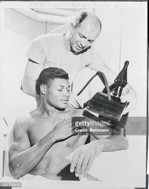 Dick Klein, University of Illinois trainer, treats the ailing shoulder of All-American halfback J.C. Caroline with a diathermy machine November 4th....