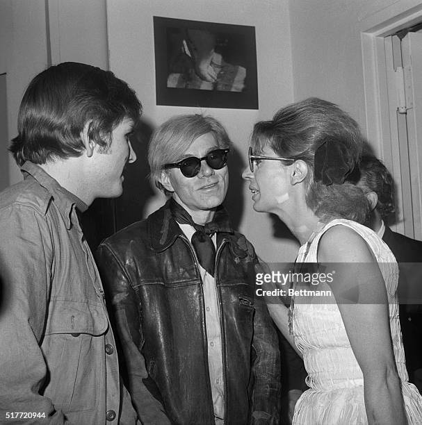 Artist Andy Warhol speaking with friends at a party at the Bleeker Street Cinema.