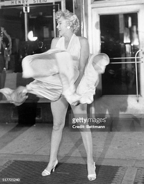 Actress Marilyn Monroe tries to hold down her dress as wind from a subway grate blows it upward during filming of The Seven Year Itch motion picture...