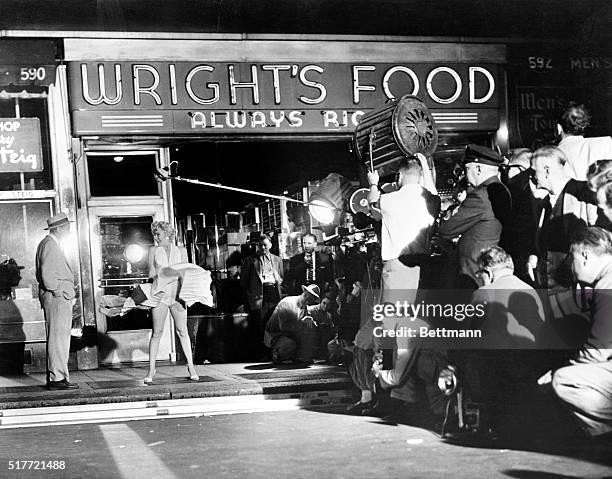 Scene outside a food store at 51st Street and Lexington Avenue early today as Marilyn Monroe stood over a subway grating and had her skirts blown up...