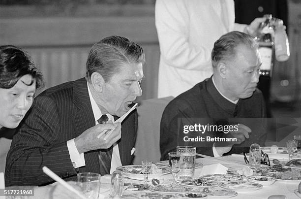 Peking, China: President Reagan eats with chopsticks at banquet at the Great Hall of the People hosted by Chinese premier Zhao Ziyang. Reagan is on...