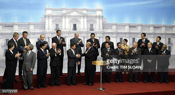 Leaders of the Asia-Pacific Economic Cooperation shake hands and applaud after Chilean President Ricardo Lagos delivered the closing speech at the...