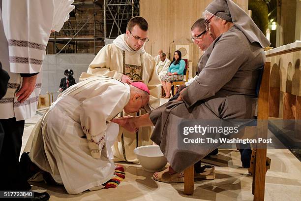 Archbishop Carlo Maria Vigano, the Vatican's ambassador to the US, finishes washing the foot of Sister Antonia Sanchez at the Basilica of the...