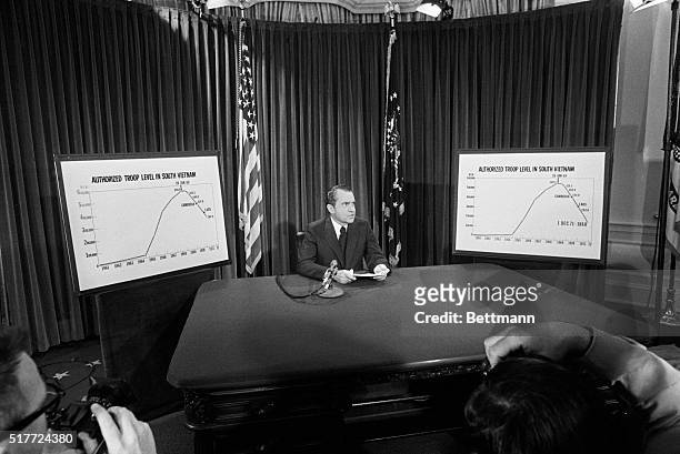 President Nixon is flanked by chart he used to illustrate his televised speech from the White House 4/7 in which he announced he will withdraw an...