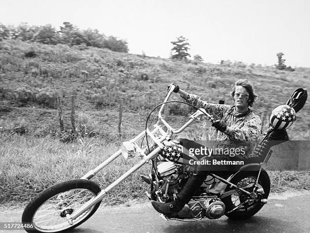 Actor Peter Fonda rides a cool sleek motorcycle - known to motorcycle enthusiasts as a "chopper" bike with a "raked" front--in a scene from his...
