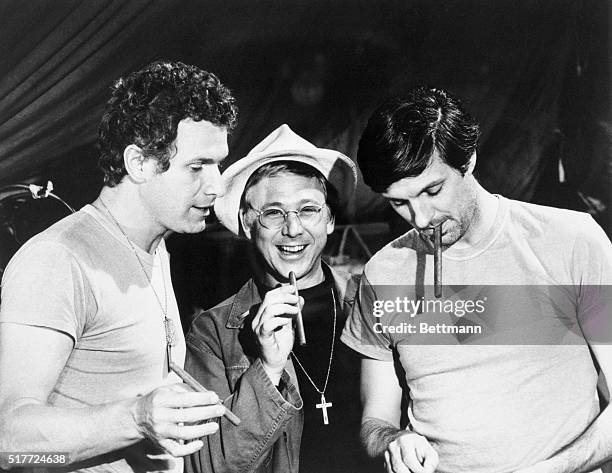 Wayne Rogers, William Christopher, and Alan Alda hold cigars as they act on the television series M*A*S*H which aired from 1972-1983. Alda played...