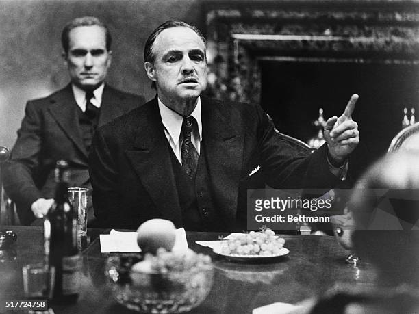 Marlon Brando as Don Vito Corleone in The Godfather, for which he won an Oscar for Best Actor. Behind him is Robert Duvall, playing Tom Hagen, the...