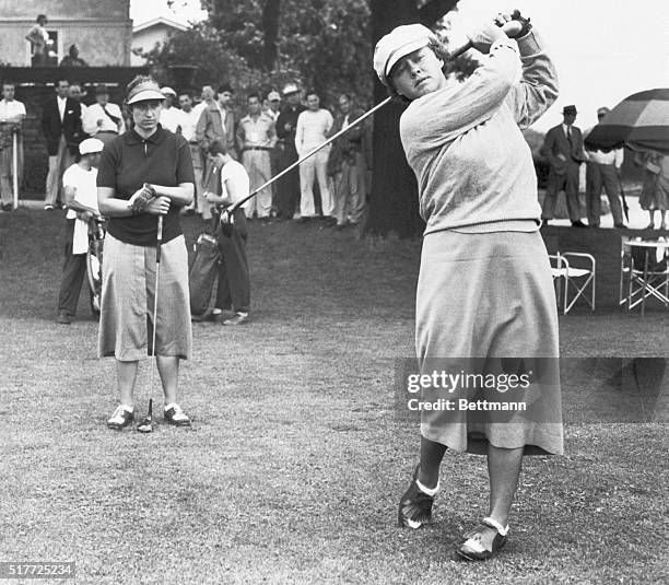 Pat O'Sullivan watches as Patty Berg drives from the first tee during the final round of the U.S. Women's Western Open at the Whitemarsh Valley...