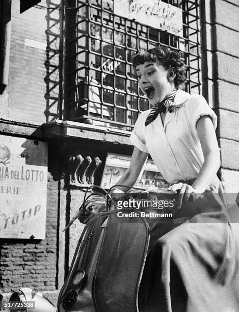 Audrey Hepburn gleefully drives a motorscooter on the set of Roman Holiday.