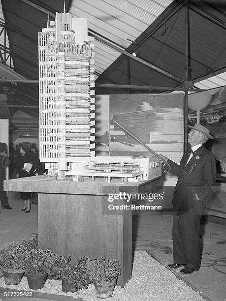 New York, NY: A dream in steel and glass. World famous architect points with his cane to a model of the Price Tower in Oklahoma, which he designed...