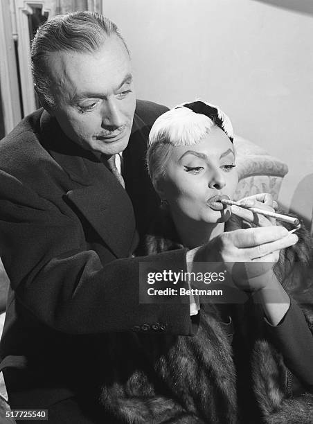 Rome, Italy: That looks like a triple king-size cigarette which perfect gentleman Charles Boyer is lighting for Sophia Loren, who is called a perfect...