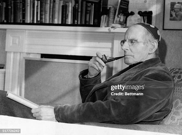 Sean O'Casey: Irish Playwright relaxing with pipe and book. Photograph, 1950.