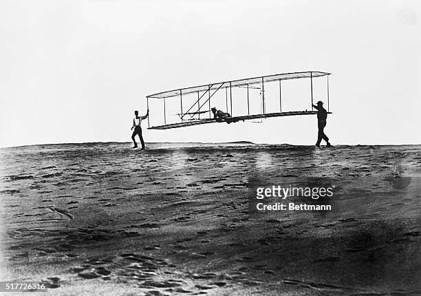Orville Wright getting ready to fly in a glider in 1902, just over a year before the successful test of a powered airplane, at Kitty Hawk. He is...