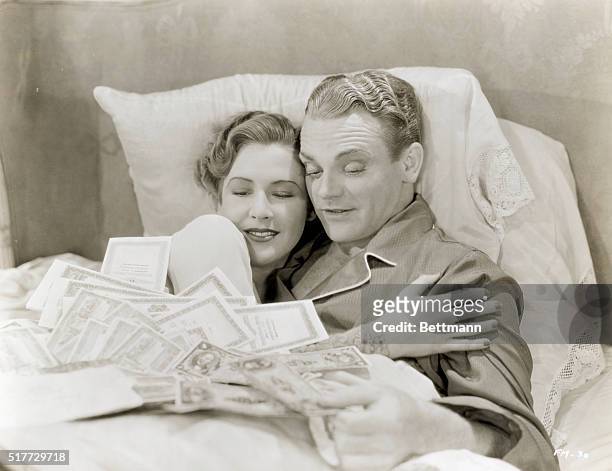 James Cagney and Mae Clark looking at a pile of money spread across the bed in the 1933 movie Lady Killer.
