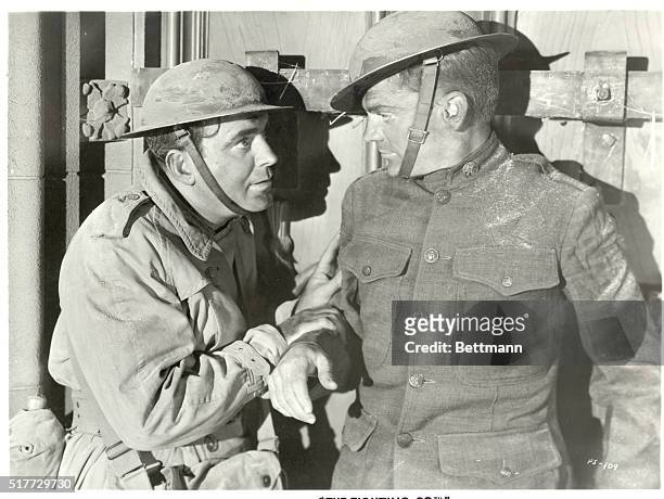 Picture shows a scene from the movie, "The Fighing 69th". Pat O'Brian who plays Father Duffy, is shown speaking to James Cagney on the battle field....