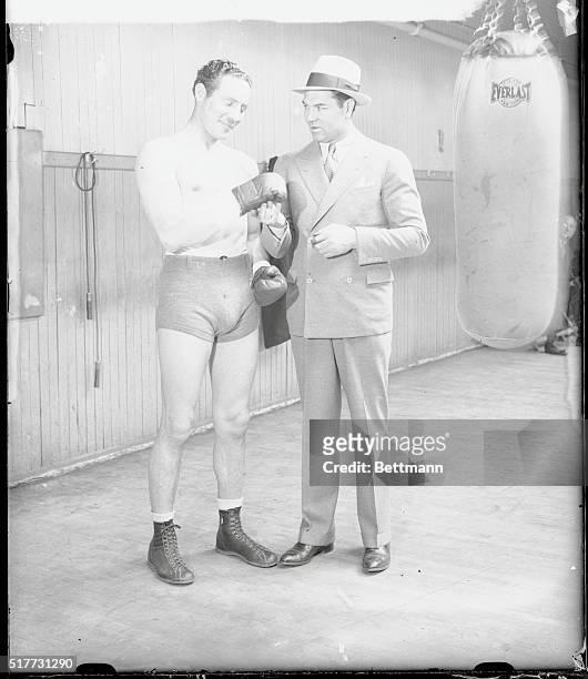 Jack Dempsey, former heavyweight champion of the world, examines the sparring gloves of Max Baer, whose match with Max Schmeling on June 8th at the...
