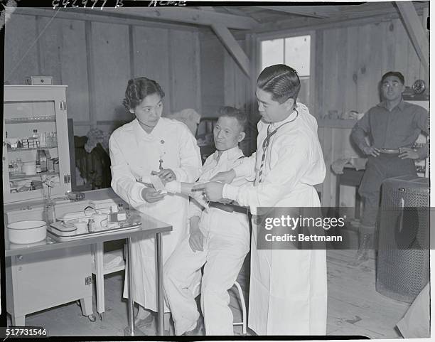 One of the first patients at the Manzanar War Relocation Center hospital, March 27, 1942. Left to right, nurse, Miss Fumiko Ghohata, Frank Saito, and...