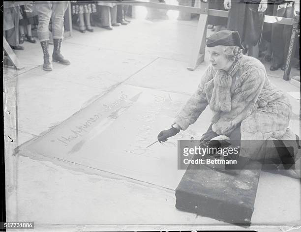 Hollywood, California, USA: Miss Diana Winyard, who plays the leading role in Cavalcade, inscribing her signature in the cement walk in the forecourt...