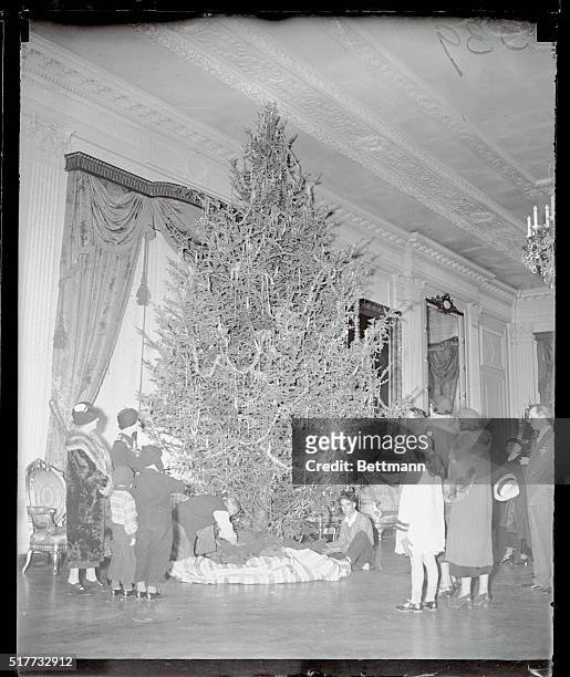 White House visitors stop to watch the final decorations go on the White House Christmas tree in the executive mansion's East Room. The President and...