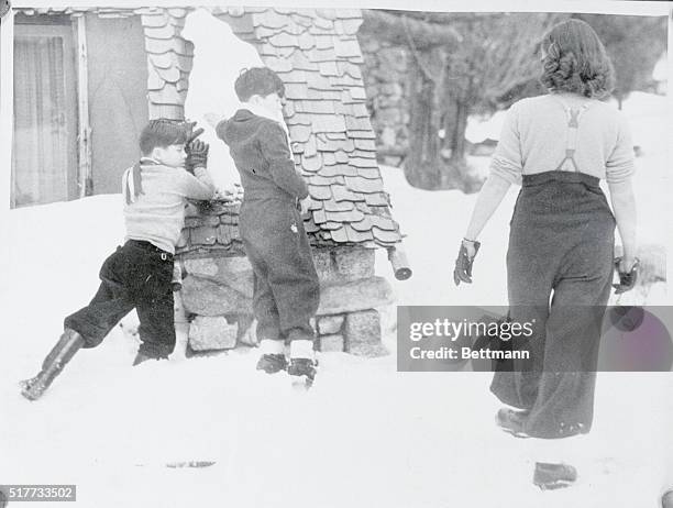 Paulette Goddard whose name has been linked romantically with Charley Chaplin, is shown at play in the snow with Chaplin's sons, Charles Jr., , and...