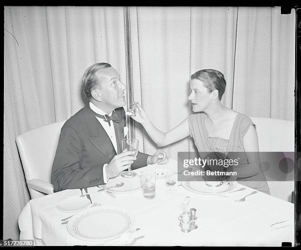 Beatrice Lillie, British comedienne, offers Noel Coward, playwright, a lump of sugar for his coffee at the Rainbow Room, swanky nightclub in...