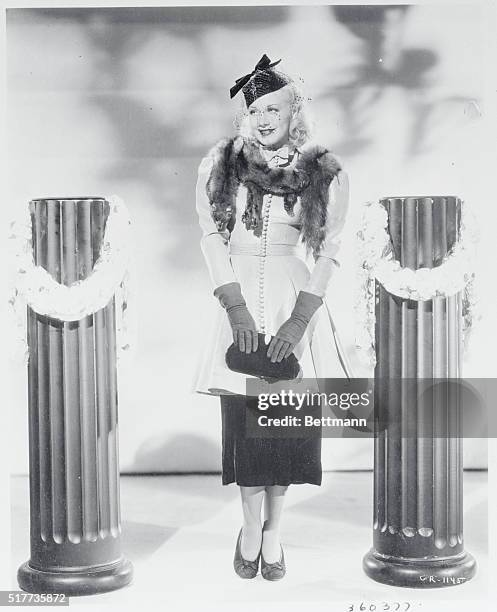 Ginger Rogers' metal cloth tunic is of turquoise and silver, made with big shoulders, slim waist and flared skirt. The whole effect is on the...