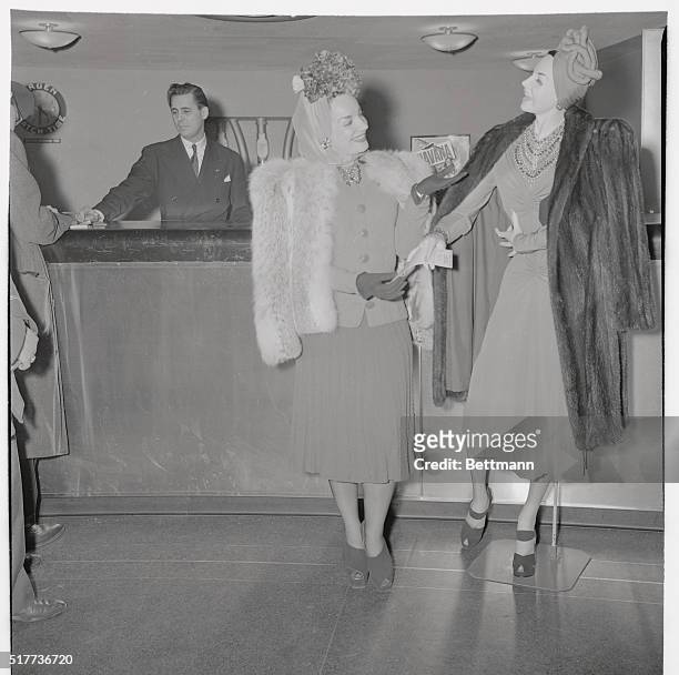 Carmen Miranda hands a life-size manikin, twin, of herself a ticket to Rio de Janeiro, which she had just purchased at the Pan American Airways...
