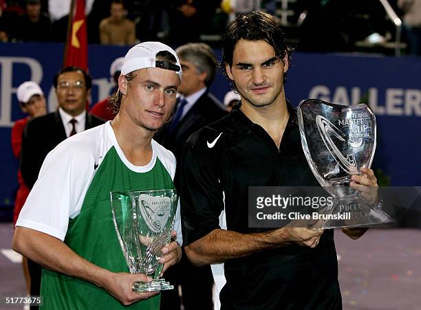 Lleyton Hewitt of Australia and Roger Federer of Switzerland hold up their trophies after the men's final at the Tennis Masters Cup November 21, 2004...