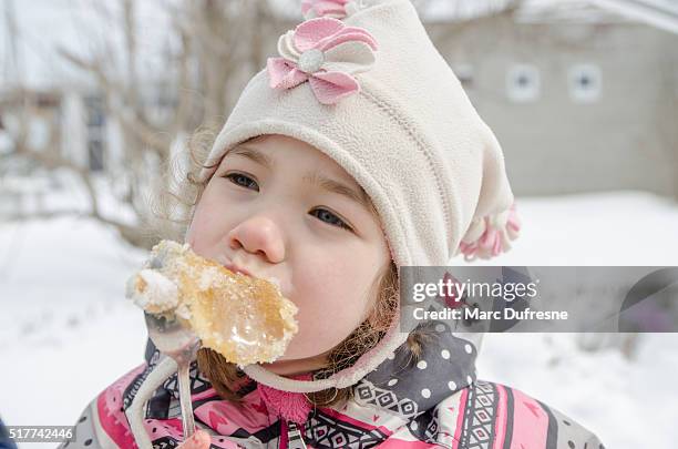 junges mädchen essen ahornsirup-toffee außerhalb - sugar shack stock-fotos und bilder
