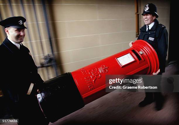 Police man laughs as he helps to carry a post box in to the quadrangle of Buckingham Palace as part of the 'Avenue of Design' a showcase of iconic...