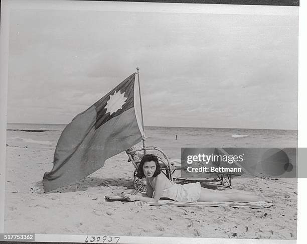 Ruth Lee, of New York and Miami Beach, hostess at Ruby Food's restaurant in Miami Beach, takes no chances when she suntans at the Lord Food's beach...