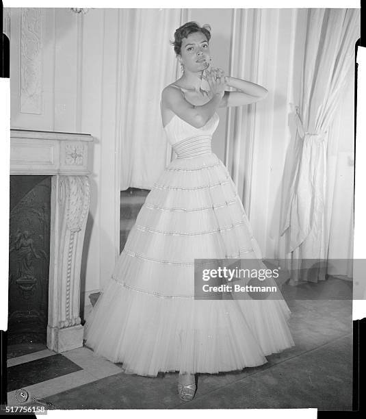 Jacques Griffe designs a debutante's dream dress in romantic white pleated tulle. Narrow strips of silver and blue ribbon ring the dress, accenting...